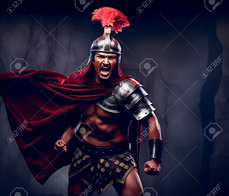 Brutalny wojownik starożytnej Grecji o muskularnym ciele w mundurze bojowym krzyczy w agonii bitewnej
