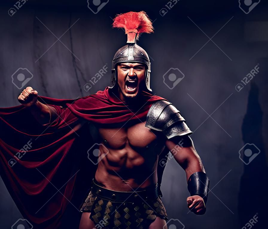Der brutale antike Griechenland-Krieger mit einem muskulösen Körper in Kampfuniformen schreit vor Kampfqualen