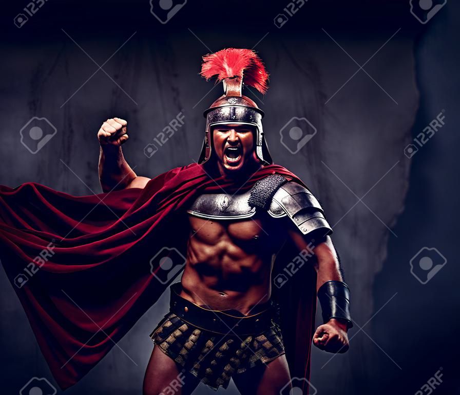 Brutal guerrero de la antigua Grecia con un cuerpo musculoso en uniformes de batalla grita en agonía de batalla
