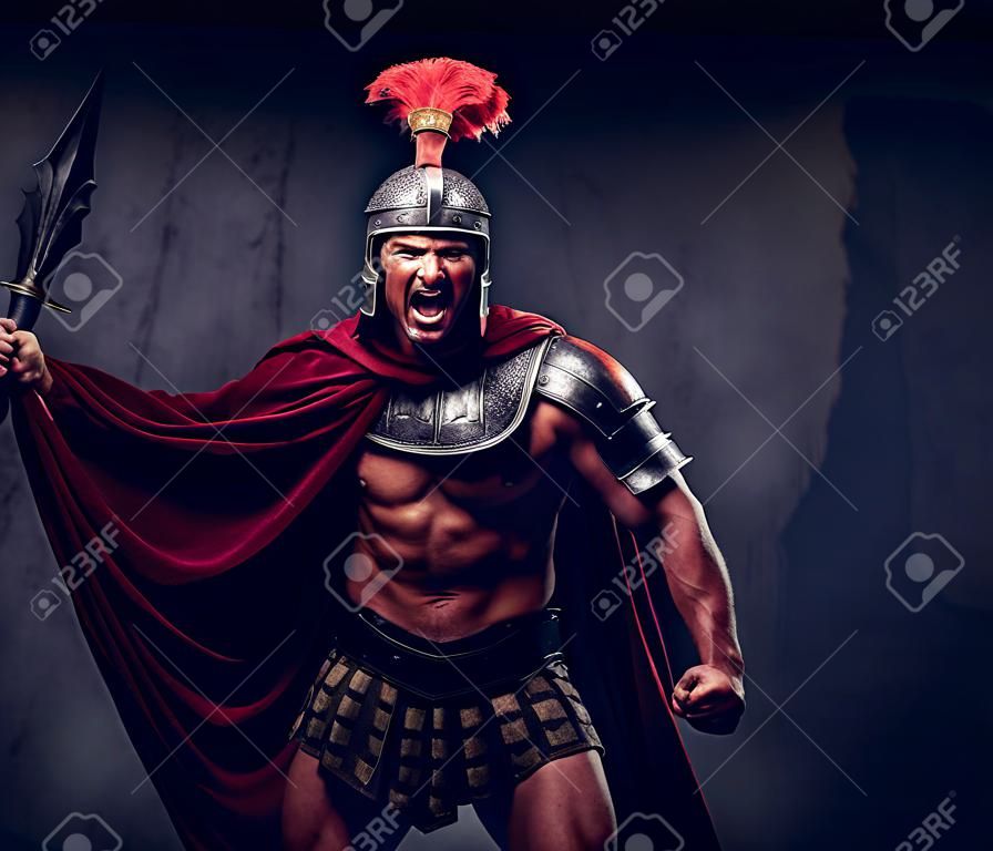 Brutalny wojownik starożytnej Grecji o muskularnym ciele w mundurze bojowym krzyczy w agonii bitewnej