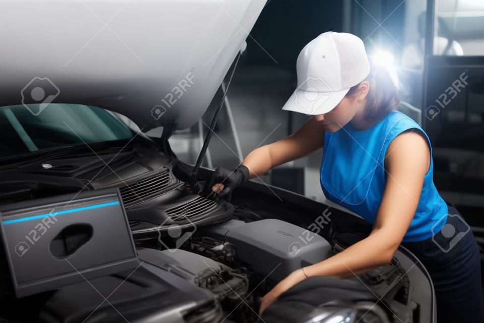 집중된 남자 여자가 자동차 서비스에서 컴퓨터의 도움으로 자동차 진단을 하고 있습니다.