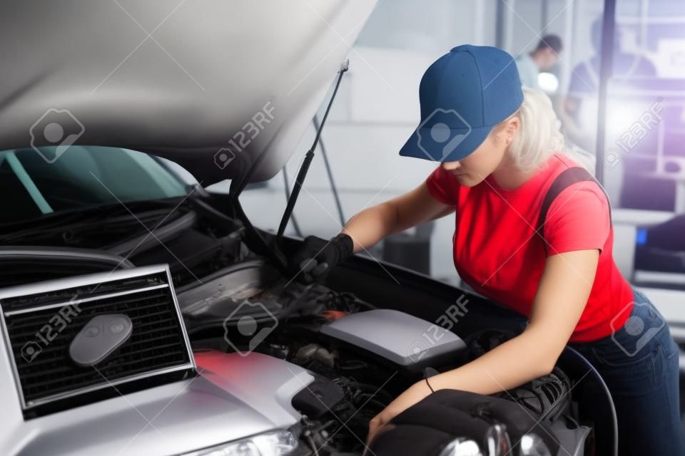 焦点を当てた男の女性は、自動サービスでコンピュータの助けを借りて車の診断を行っています。