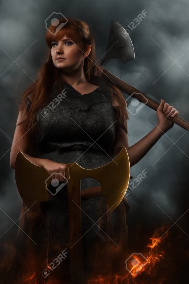 Armoured scandinavian lady with long brown hairs holding two huge axes in atmospheric smokey background.