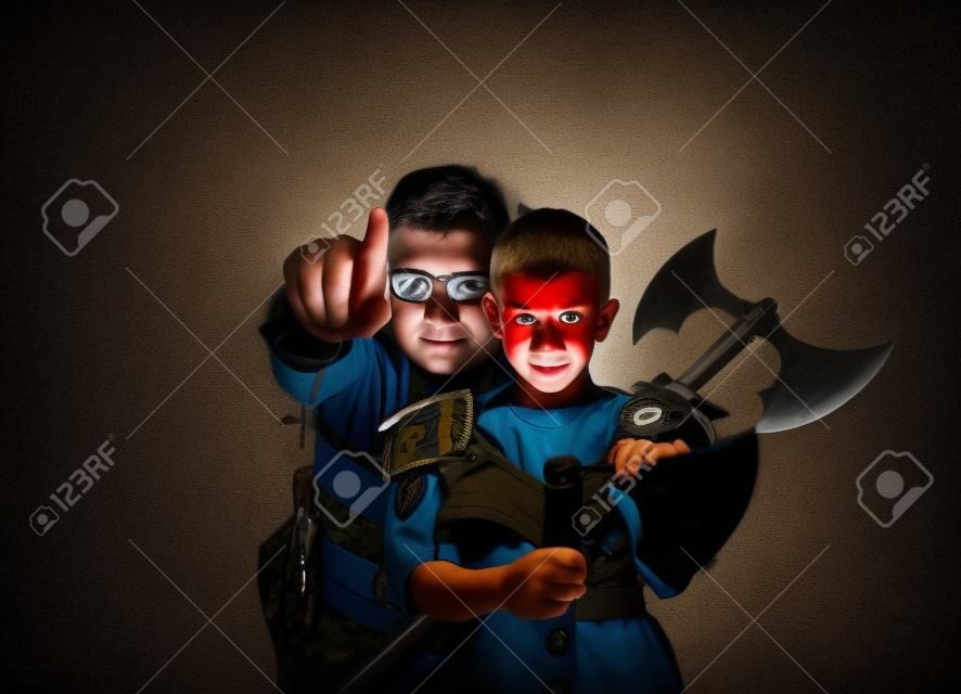 Military boy and his father warrior behind him pointning a finger at camera in dark background.