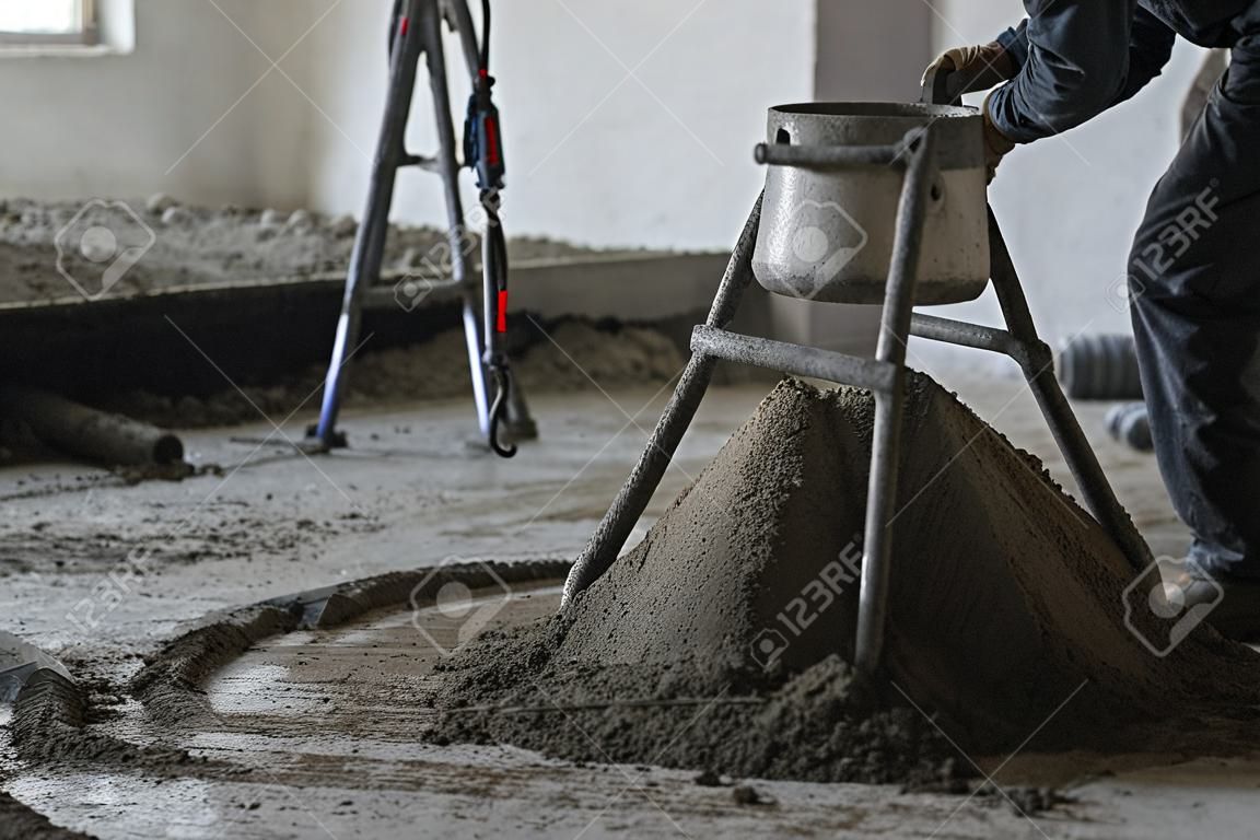 worker pouring concrete with cement mixer at construction site, close-up