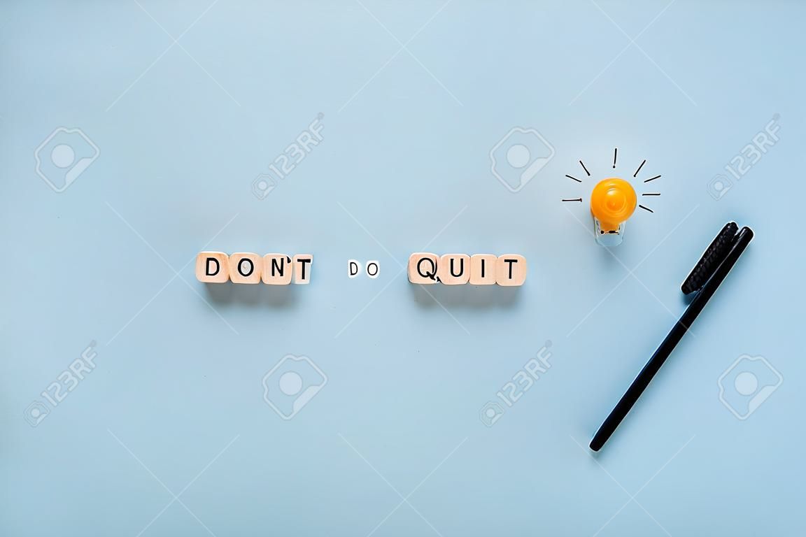„Don’t quit or do it“-Zeichen auf Holzwürfeln in einem konzeptionellen Bild von Bildung und Karriere. auf blauem Hintergrund.