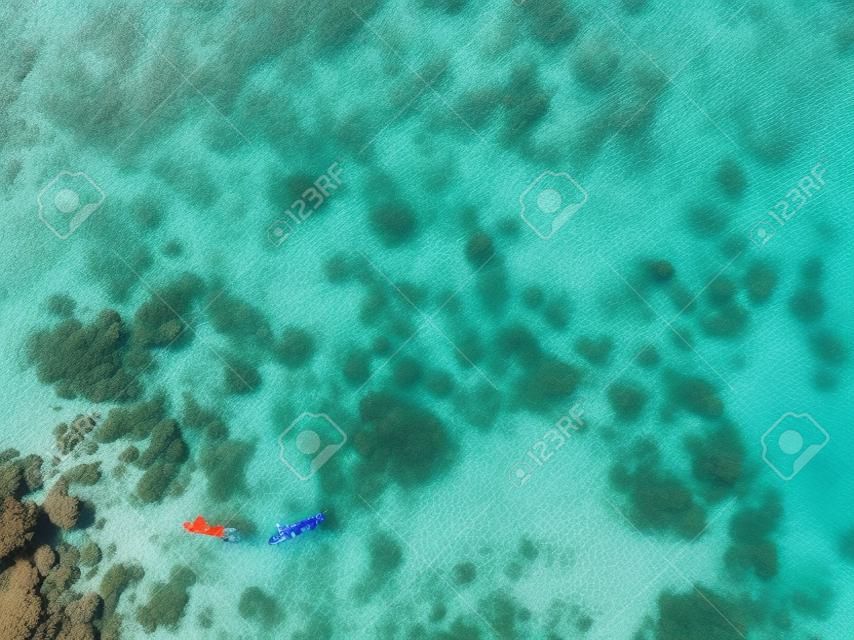 Couple snorkeling in the blue sea ocean and coral background aerial top view