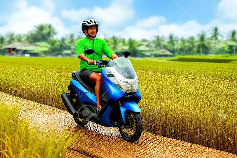 Male traveler on a bike among a rice field. Tourist travels to Bali