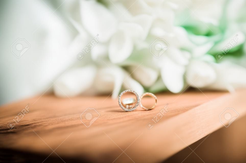 Fedi nuziali su un supporto di legno sullo sfondo del bouquet della sposa