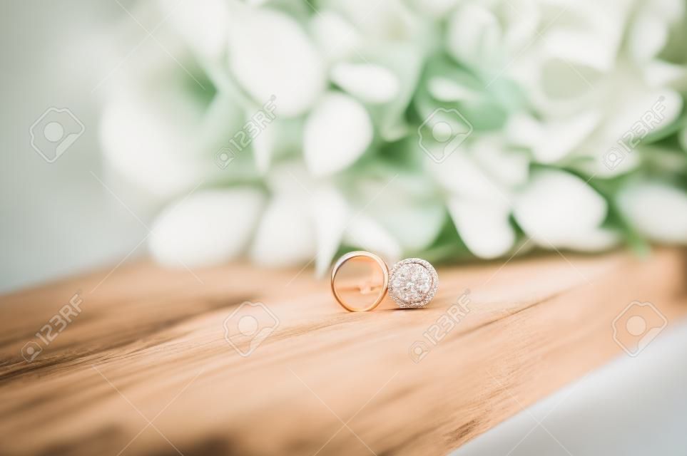 Bruiloft ringen op een houten stand tegen de achtergrond van het boeket van de bruid