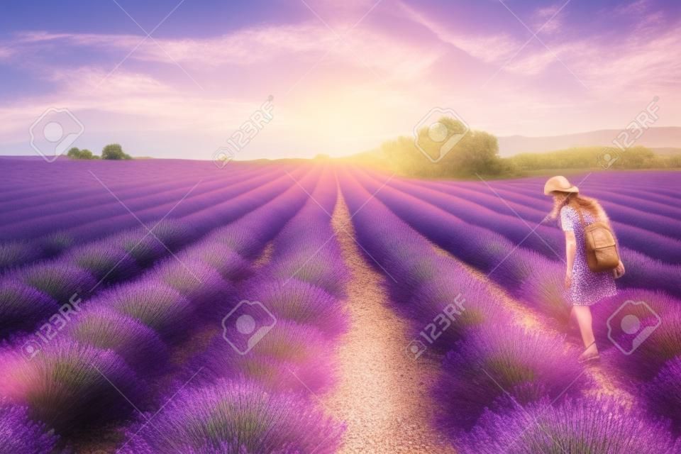 Frau geht auf Lavendelfeld bei Sonnenuntergang