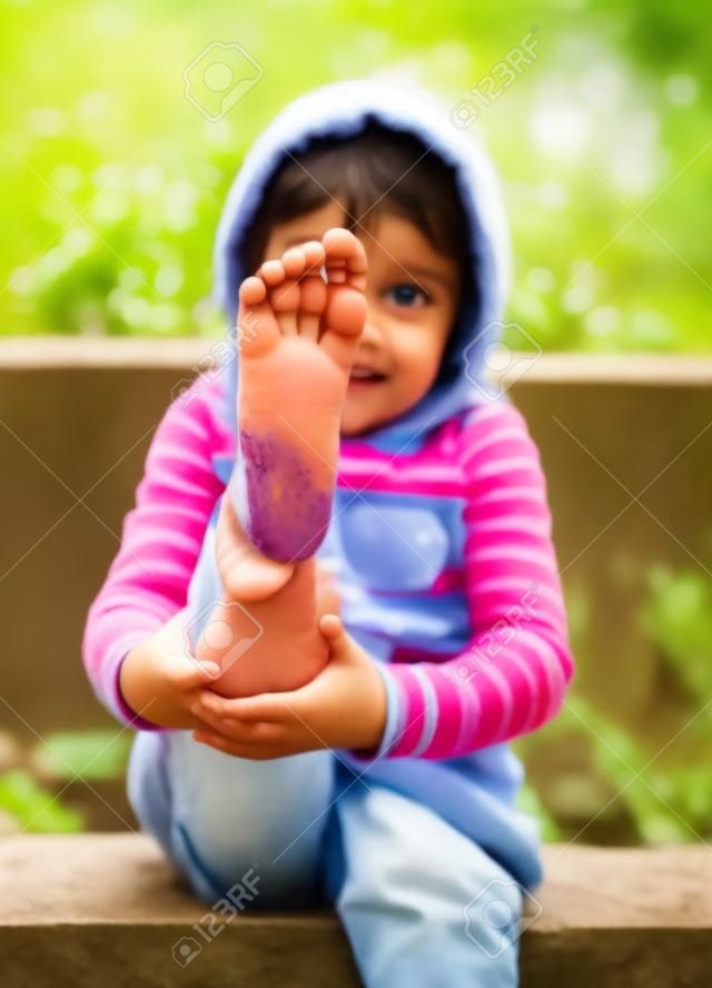 Kind zeigt schmutzigen Füße vom Spielen im Schlamm. Spiel draußen in der Natur.