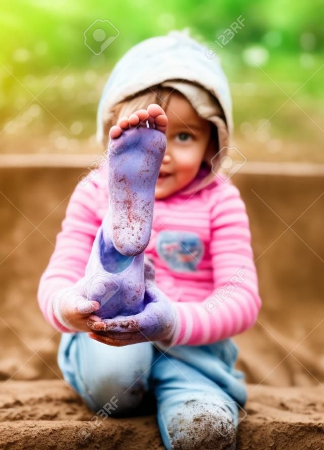 Kind zeigt schmutzigen Füße vom Spielen im Schlamm. Spiel draußen in der Natur.