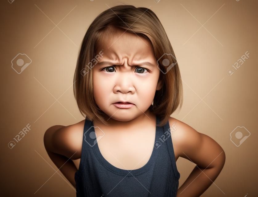 Little girl is angry, mad and looking at the camera. Emotion face.