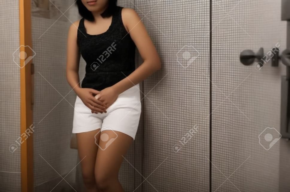 Рука азиатская женщина, держащая ее промежность, женщина должна пописать в туалет