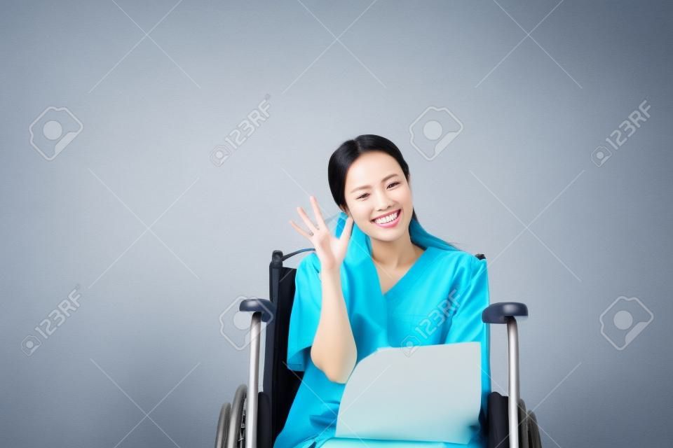 Aziatische mooie vrouw patiënten omhoog uw hand OK teken symbool en zitten op rolstoel in het ziekenhuis, gelukkig en glimlachen