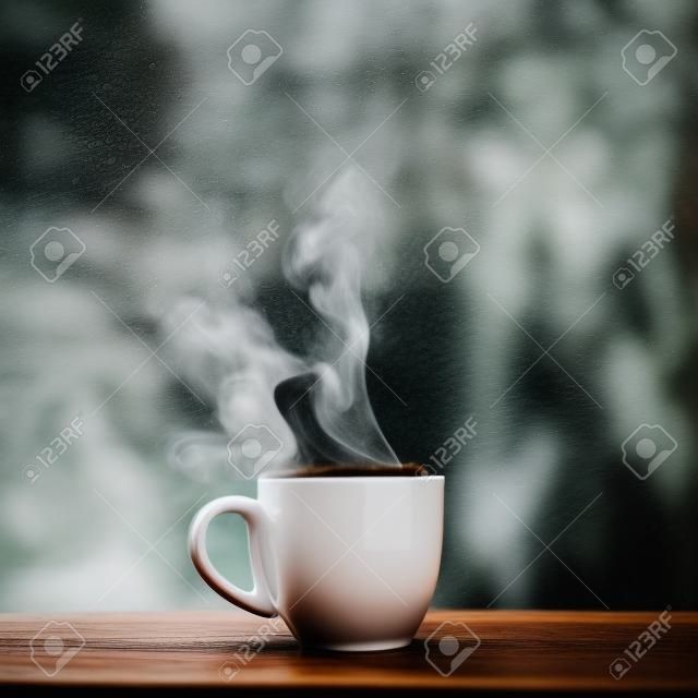 Steaming coffee cup on a rainy day window 