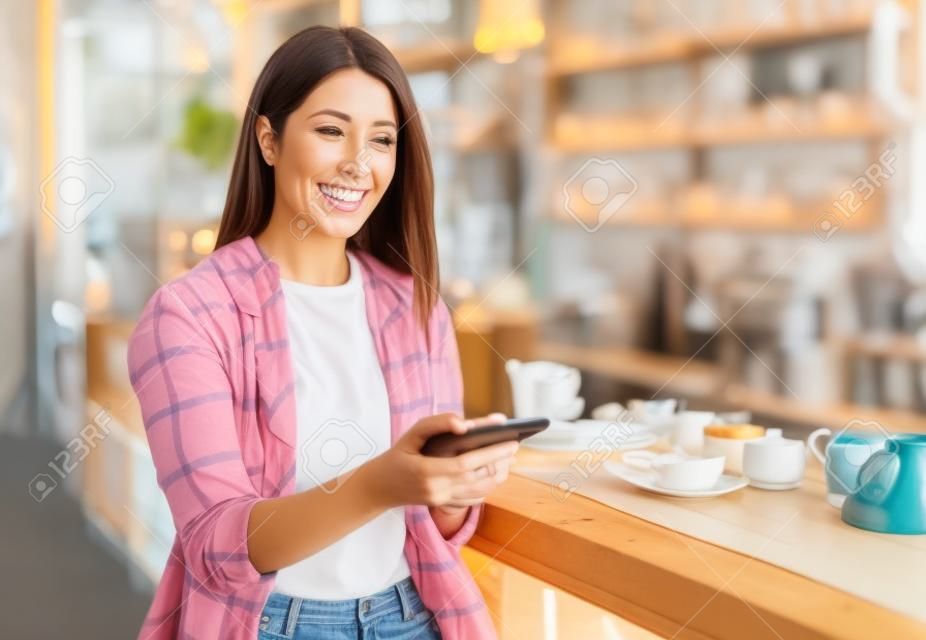 mujer feliz usando un teléfono inteligente en un café