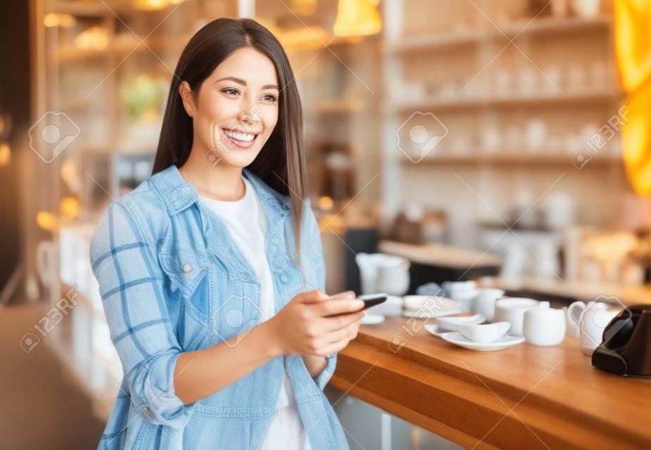 mujer feliz usando un teléfono inteligente en un café