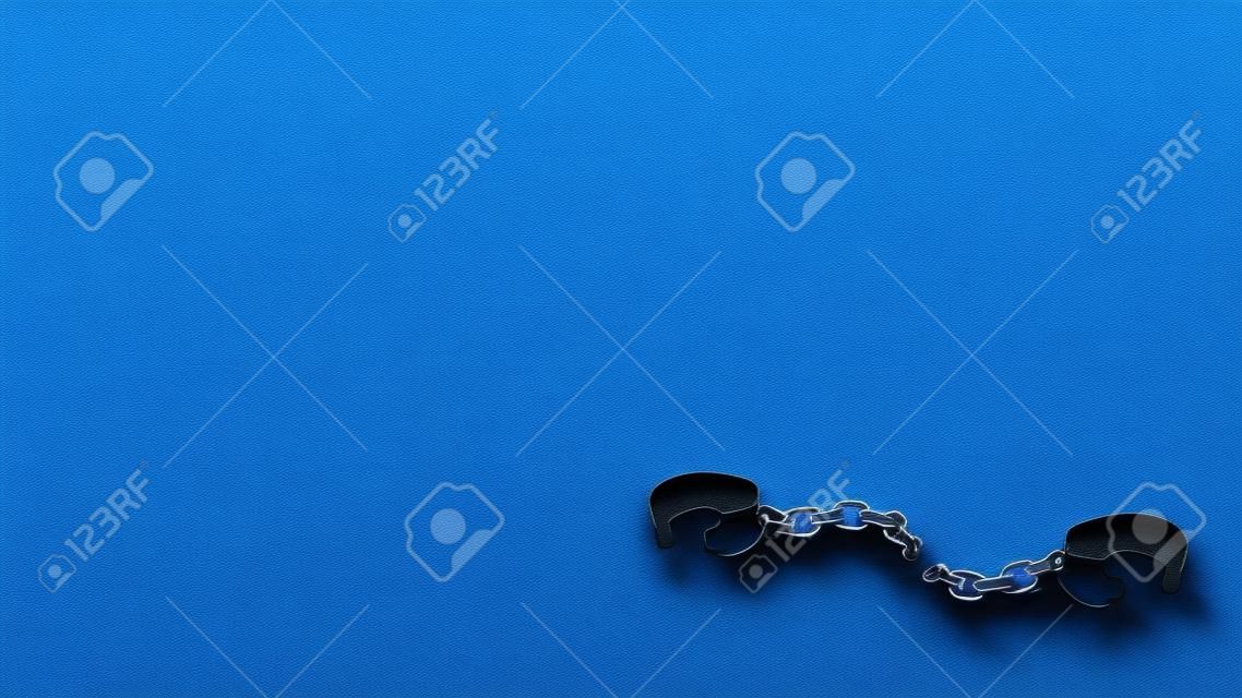 3d rendering of set of iron black handcuffs on a broken chain lying open on a blue background.