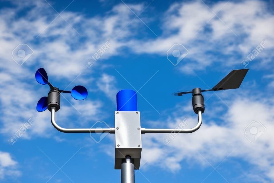 Anemometer and wind vane on blue sky. Measuring wind speed and direction.  The rotating cup anemometer is commonly used to measure wind speed.