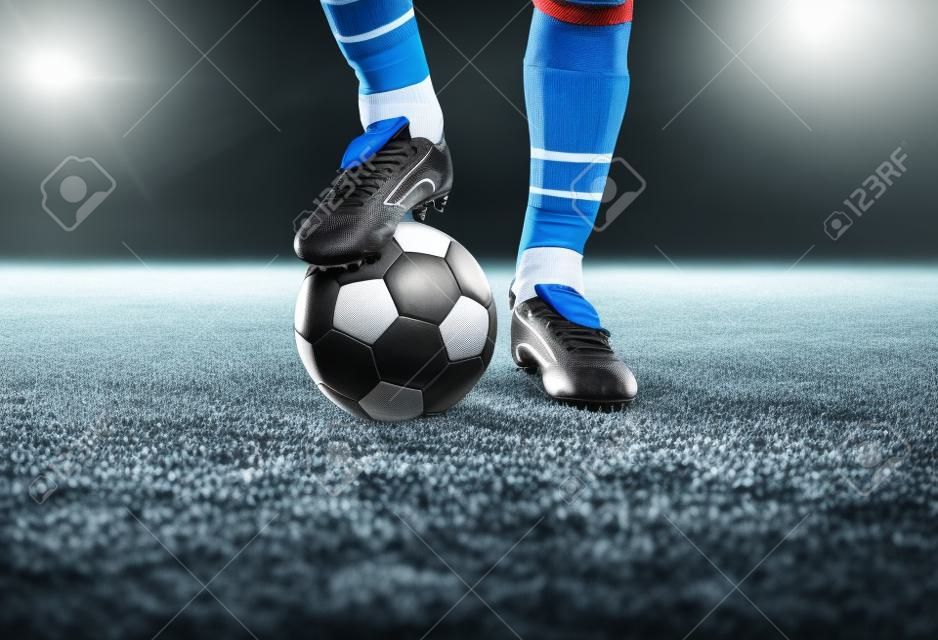 balón de fútbol con los pies en el campo de fútbol