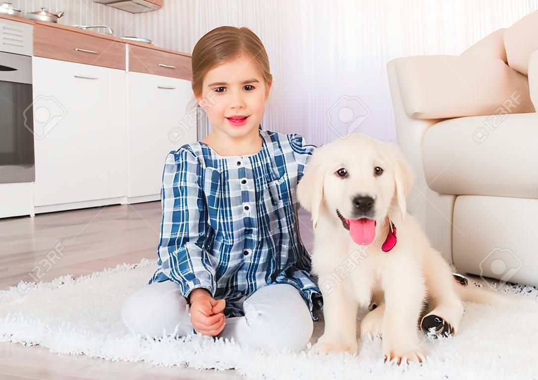 Smiling little girl sitting with cute fluffy retriever puppy at home