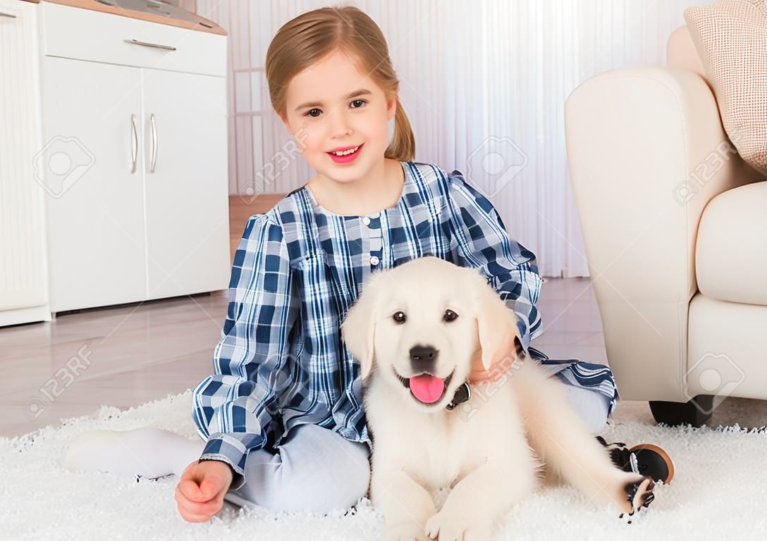 Smiling little girl sitting with cute fluffy retriever puppy at home