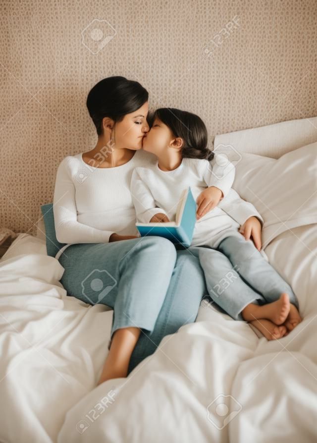 어머니와 딸이 책을 읽는 동안 침대에서 키스