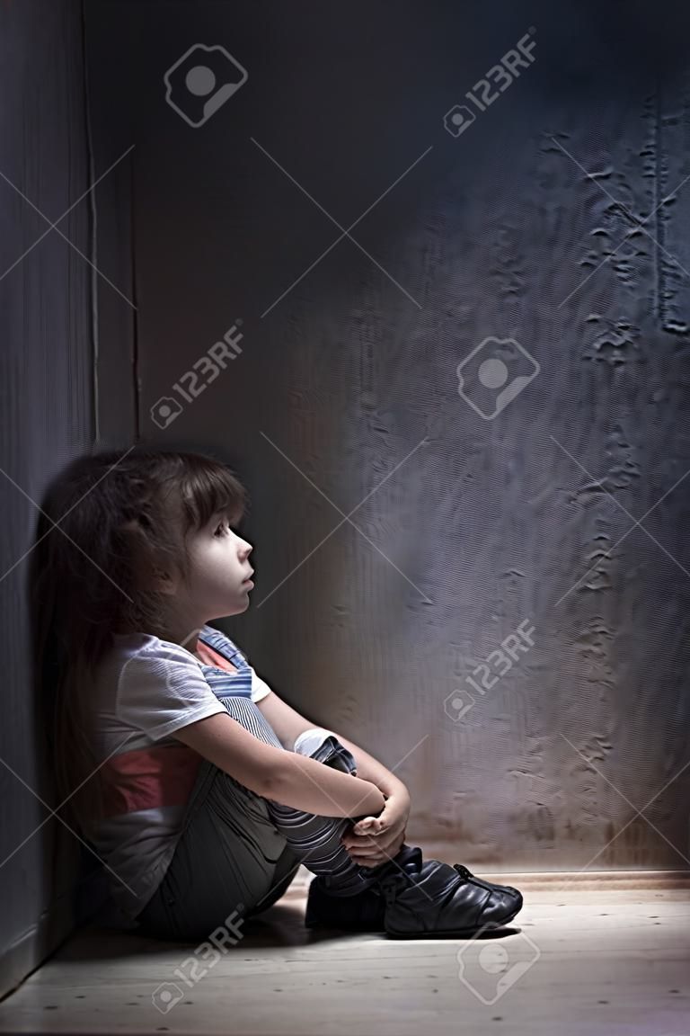 Kind allein in einer dunklen Ecke