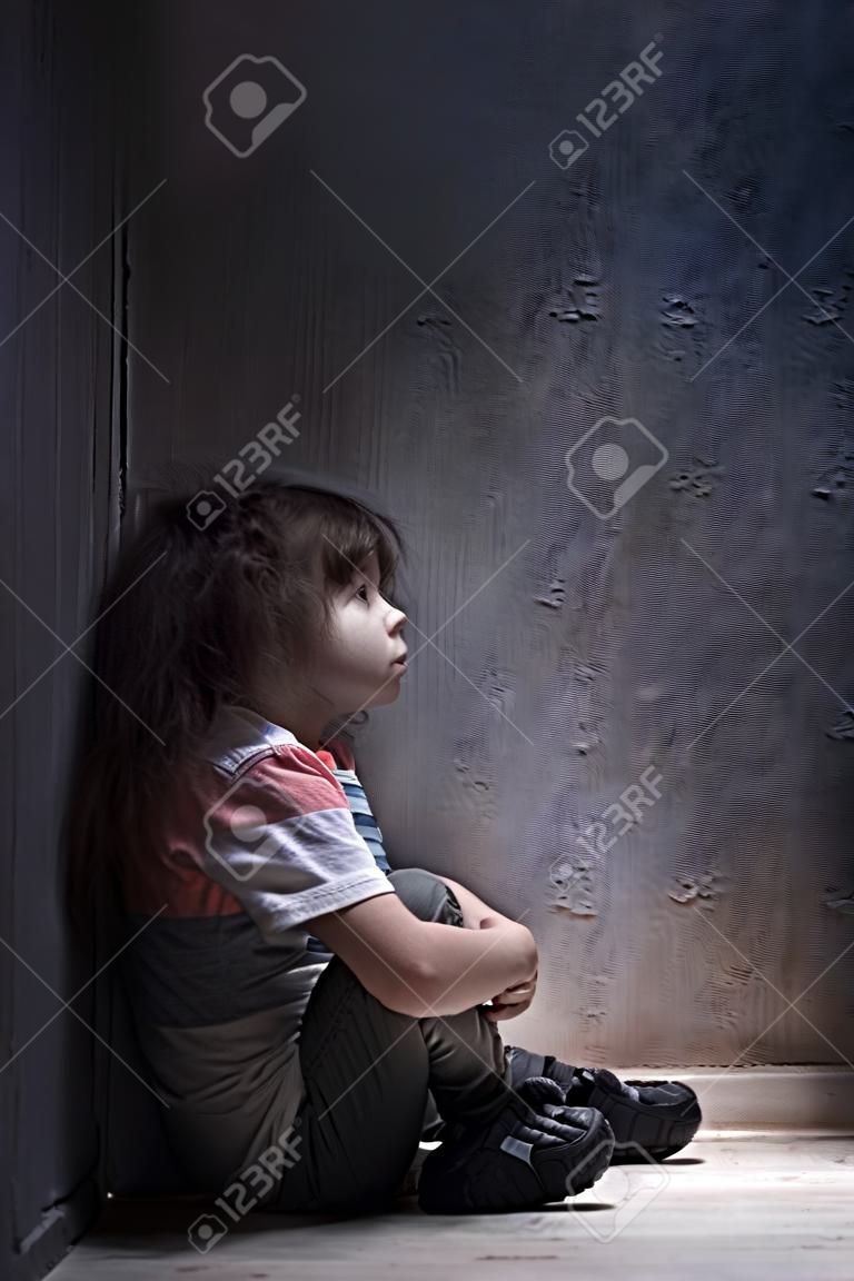 child alone in a dark corner
