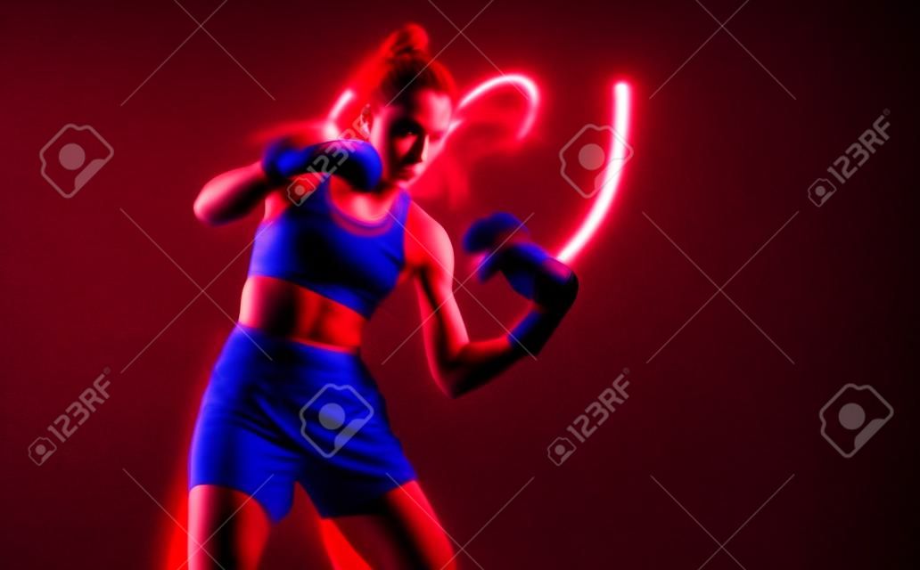 Cool female fighter in boxing bandages trains in studio in red neon light. Mixed martial arts poster. Long exposure shot