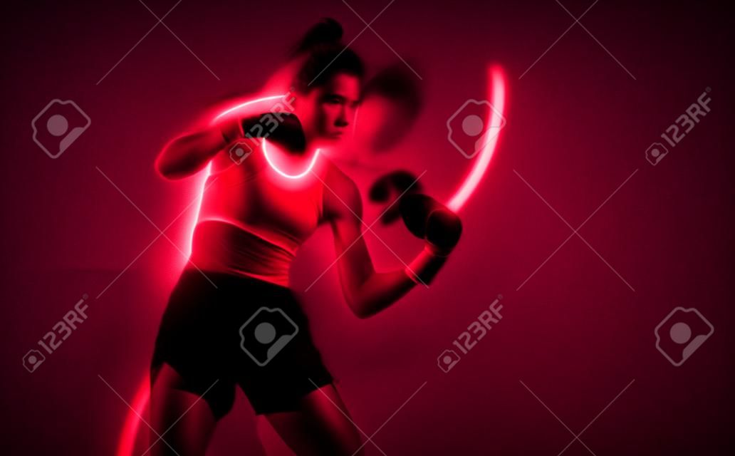 Cool female fighter in boxing bandages trains in studio in red neon light. Mixed martial arts poster. Long exposure shot