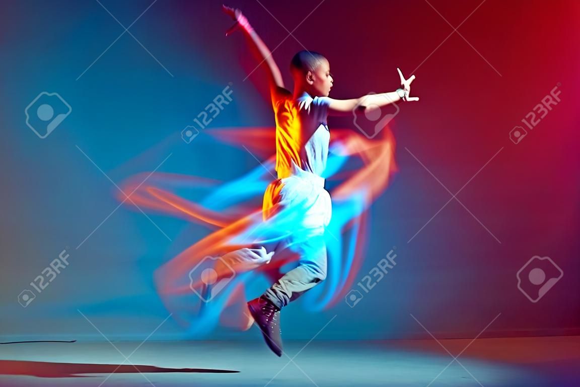 Jumping jovem menina com cabelo curto legal dançando na luz de néon colorido. Anúncio escola de dança contemporânea. Longa exposição