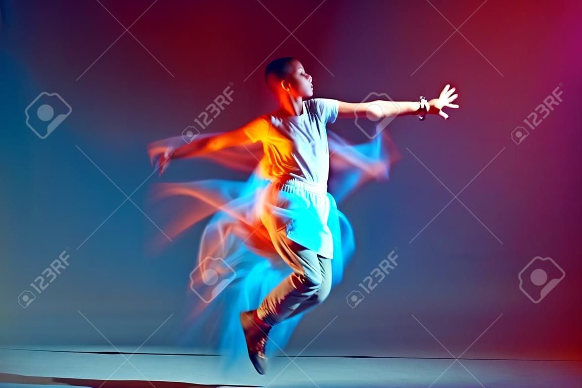 Saltando la ragazza con i capelli corti ballare alla moda in una luce al neon colorata. Annuncio scuola di danza contemporanea. Esposizione prolungata
