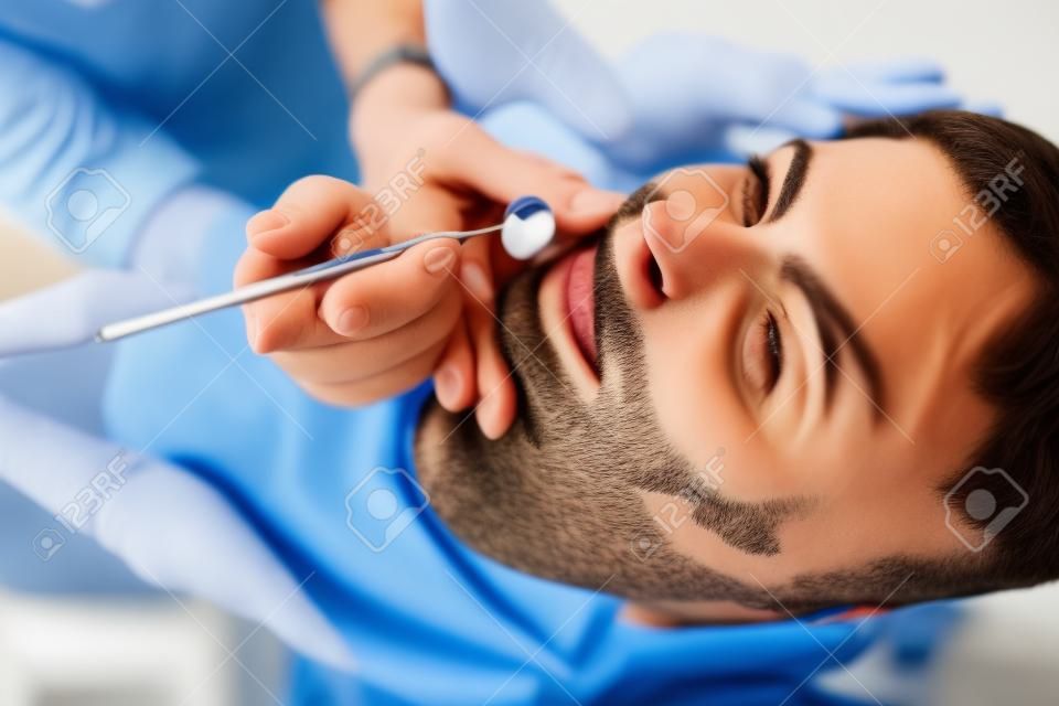 Jeune homme séduisant sur un examen du médecin dentiste.