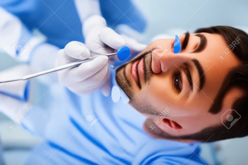 Молодой привлекательный мужчина на обзор врача стоматолога.