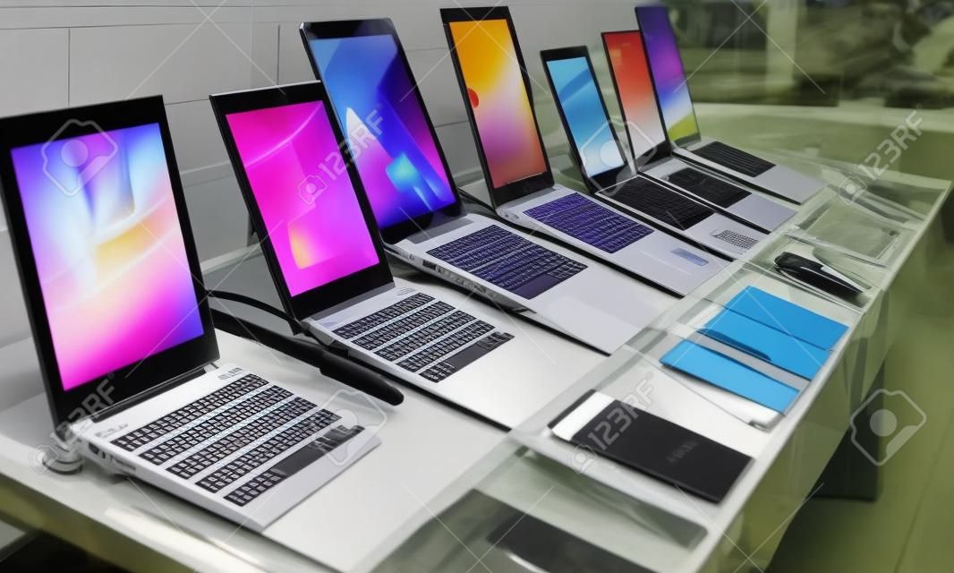 Various types of portable computers are presented for sale in the shop window.