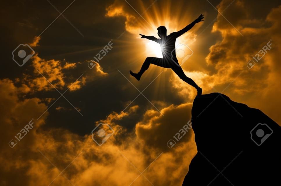 Silhouette eines Mannes von einer Klippe springen in Richtung der hellen Sonne