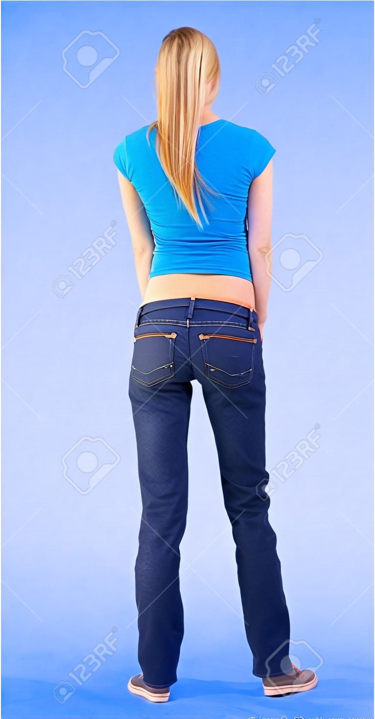 back view of standing young beautiful  blonde woman in blue t-shirt and jeans.