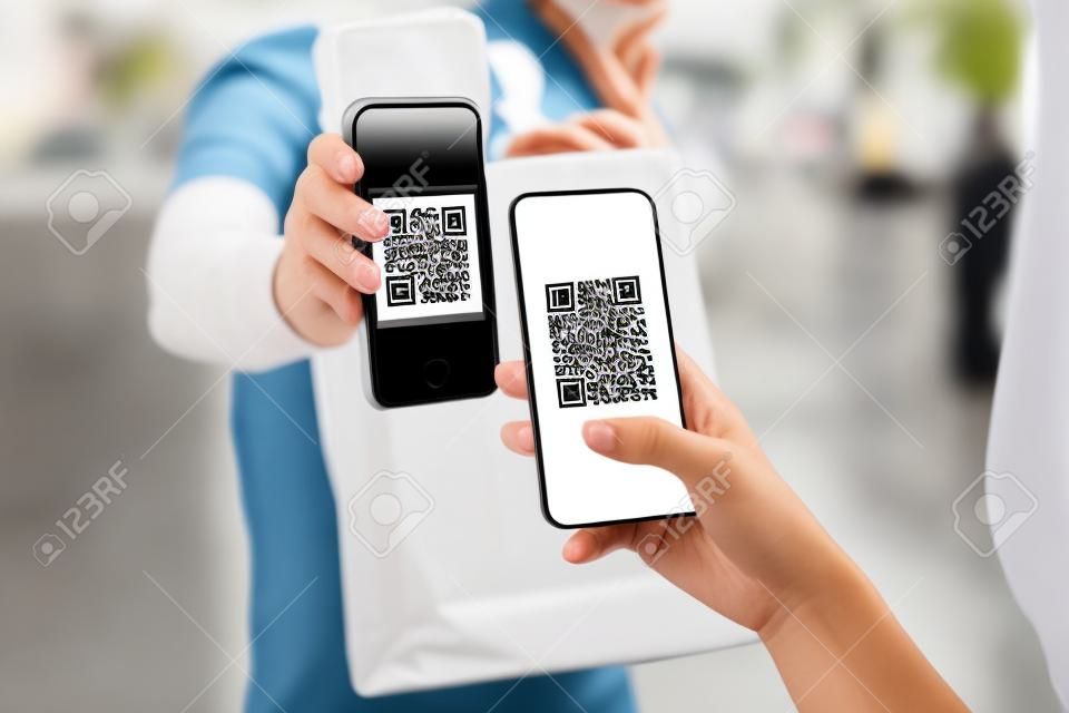 woman customer using digital mobile phone scan QR code paying for buying fresh food set bag from food delivery service man, express delivery, digital payment technology and fast food delivery concept