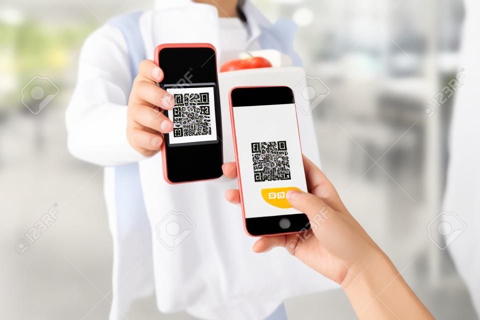 woman customer using digital mobile phone scan QR code paying for buying fresh food set bag from food delivery service man, express delivery, digital payment technology and fast food delivery concept