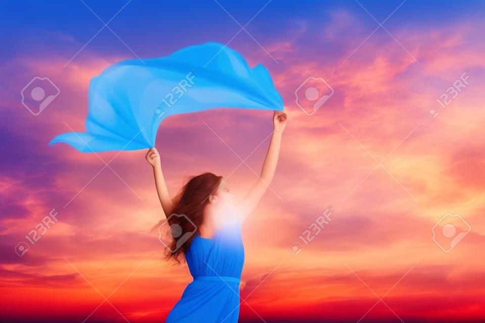 Schöne junge Frau, auf sunset Hintergrund mit blauem Gewebe.