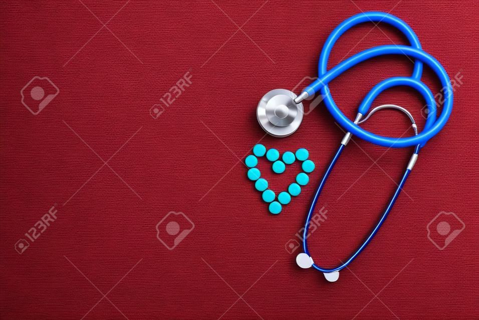 Red stethoscope with tablets, pills on blue background.