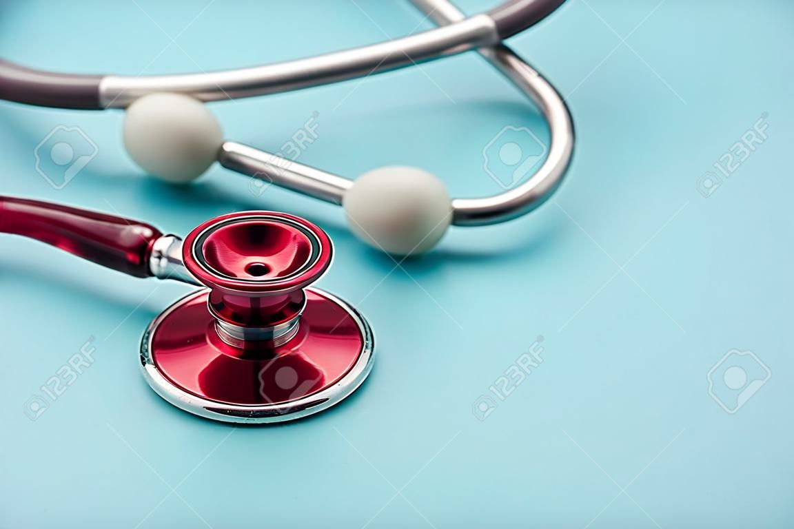 Red stethoscope on blue background. Close up. Medicine and healthcare.