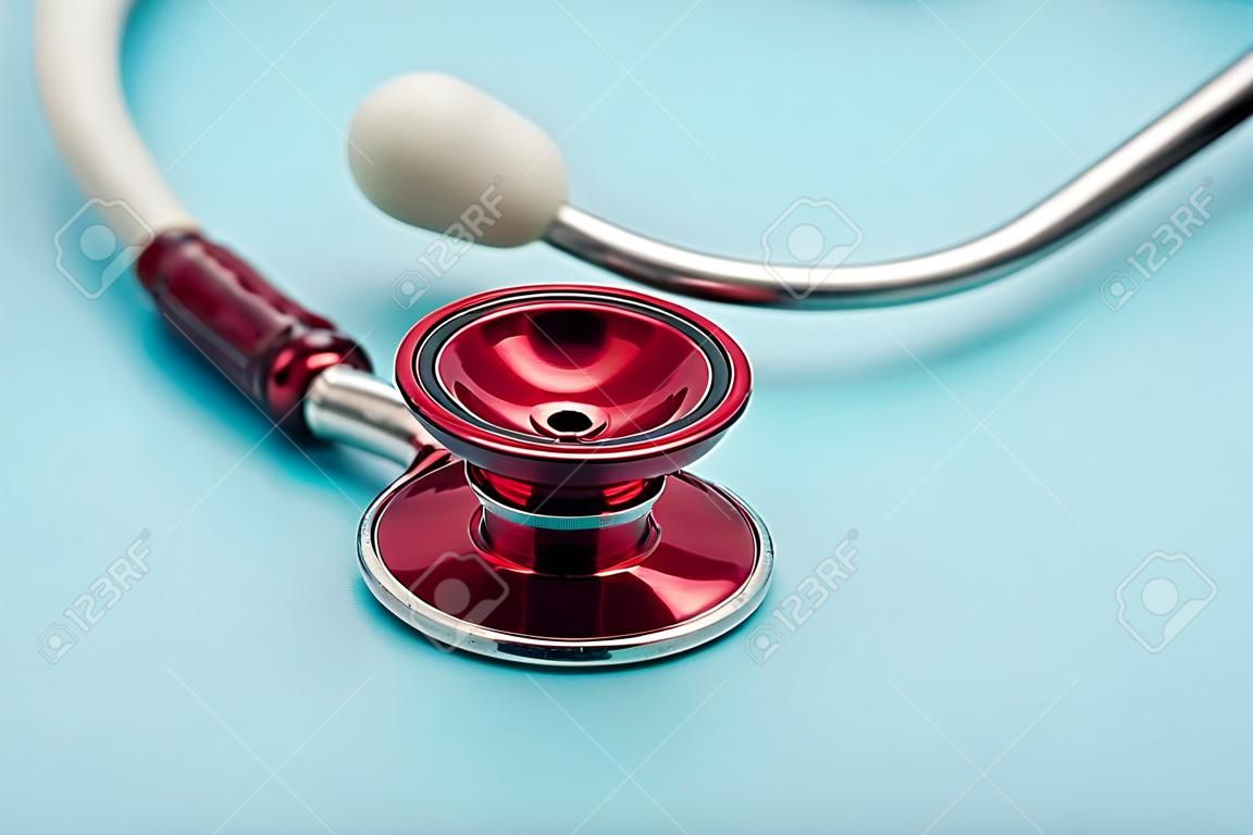 Red stethoscope on blue background. Close up. Medicine and healthcare.