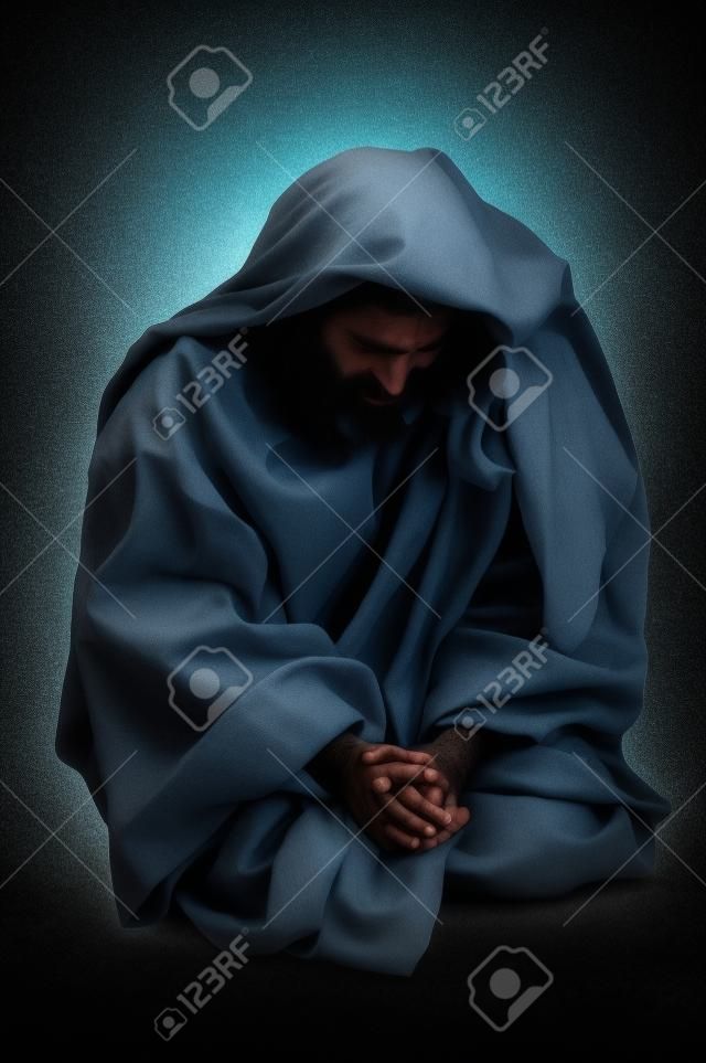 Jesus praying on his knees over a black background