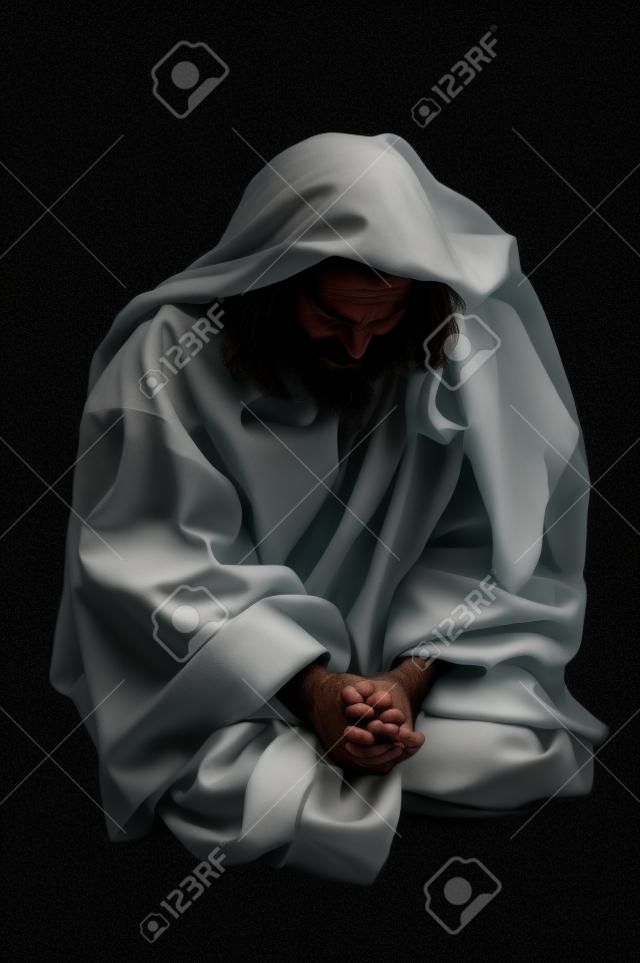 Jesus praying on his knees over a black background