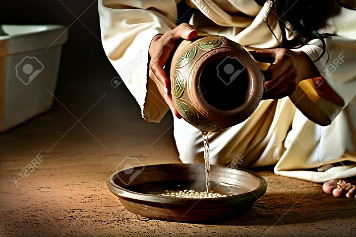Jesus pouring water from jug to pan to wash feet of disciples