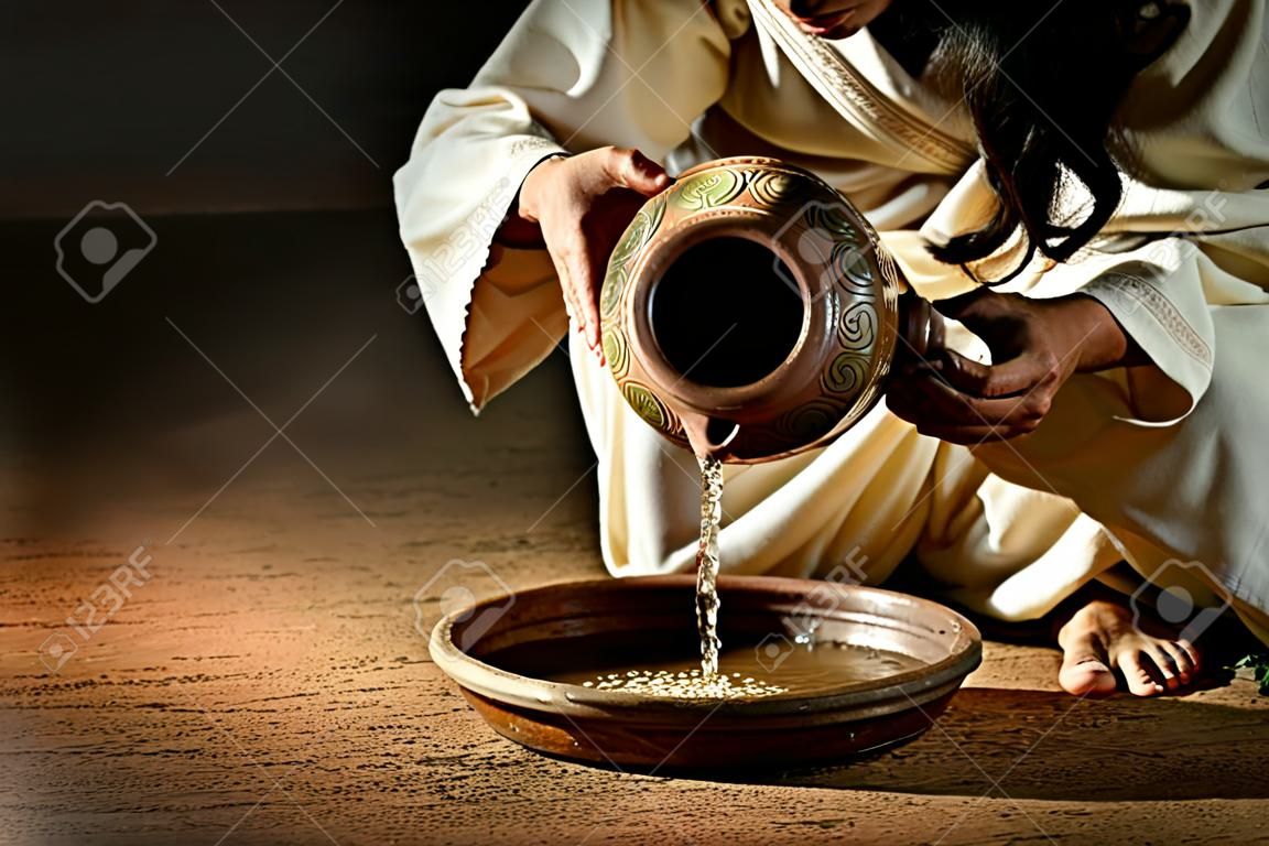 Jezus giet water van kruik naar pan om de voeten van discipelen te wassen